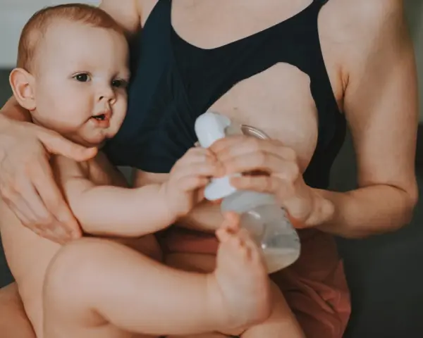 Mama karmi piersią i odciąga pokarm, pokazując, jak karmienie piersią a praca mogą iść w parze.