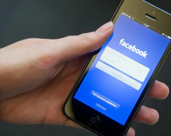 Eine Hand hält ein Smartphone mit der Facebook-Anmeldeseite.