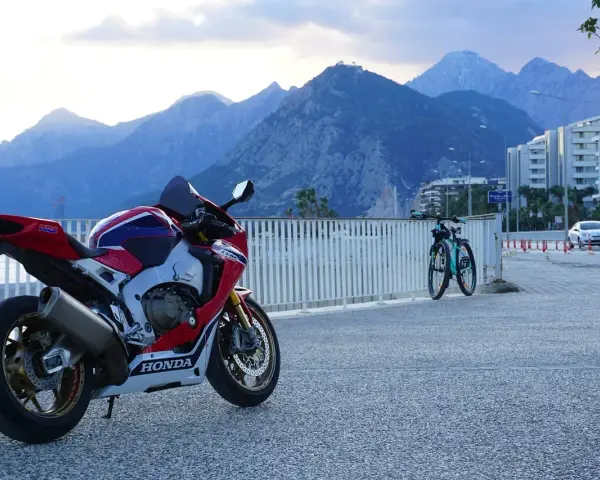 Sportowy motocykl Honda i dwa rowery na tle gór. Wyobraź sobie podróż po **tajlandii północnej** na tym sprzęcie.