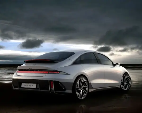 Srebrny Hyundai Ioniq 6 na plaży pod pochmurnym niebem.