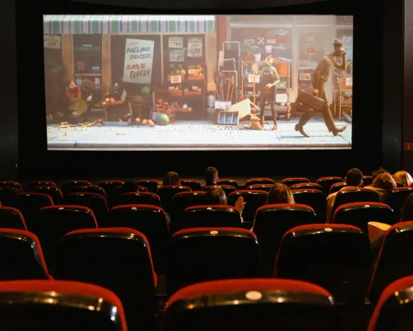 Una sala de cine con público observando una película animada. Esto es que es el cine: una experiencia compartida de historias en pantalla grande.