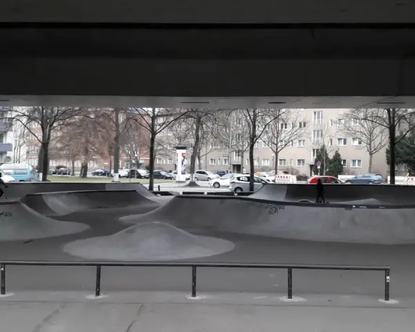 Ein leerer Berlin Skatepark unter einer Brücke. Ein Radfahrer fährt durch die Betonlandschaft.