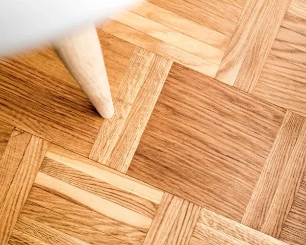 Ett vackert parkettgolv i ek, redo för renovering. En vit möbel står på golvet.