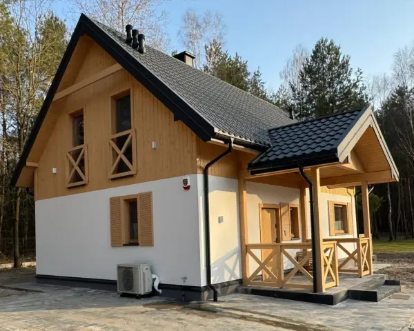 Nowy dom w lesie, drewniane elementy i biały tynk. Prowadzenie budowy domu zakończone sukcesem, gotowy do zamieszkania.