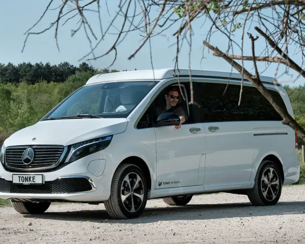 Vit eldriven husbil från Tonke parkerad på grusväg. En man med solglasögon sitter bakom ratten.