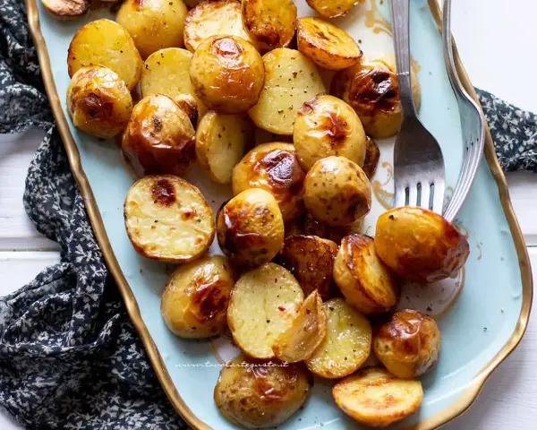 Patate novelle al forno dorate e croccanti, servite su un piatto decorato, pronte per essere gustate.