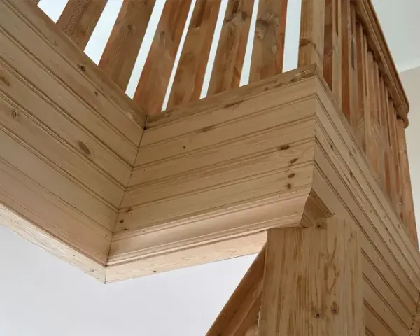 Detalles de la escalera con molduras de madera en la pared, creando un acabado rústico y acogedor.