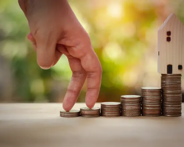 Main qui monte les marches de pièces, symbolisant la croissance et la gestion des revenus fonciers. Une maison en bois au sommet.