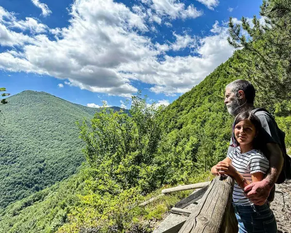 Un uomo e una bambina ammirano il panorama sui sentieri di Roccaraso, immersi nel verde lussureggiante delle montagne.