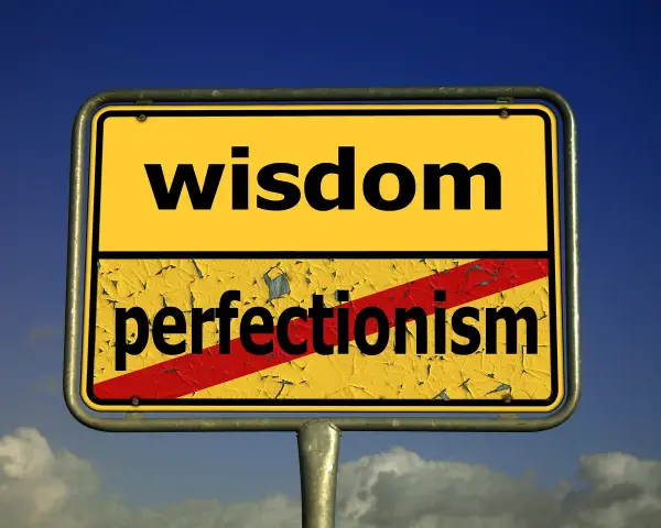 Znak drogowy z napisem "wisdom" na górze i przekreślonym "perfectionism" na dole. Symbolizuje odrzucenie perfekcjonizmu na rzecz mądrości.
