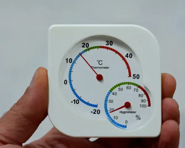 Termómetro y higrómetro en mano, mostrando cómo medir la humedad en casa.