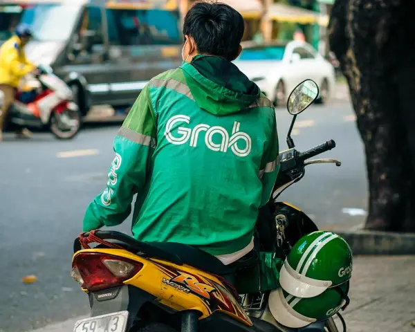 Fahrer mit Grab-Jacke wartet auf seine nächste Fahrt in Vietnam.
