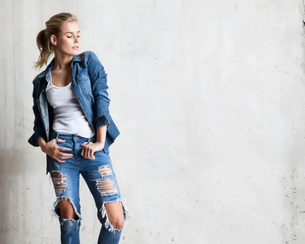 Stylowa blondynka w rozdartych jeansach i jeansowej koszuli. Inspiracja, jak nosić koszulę do jeansów.