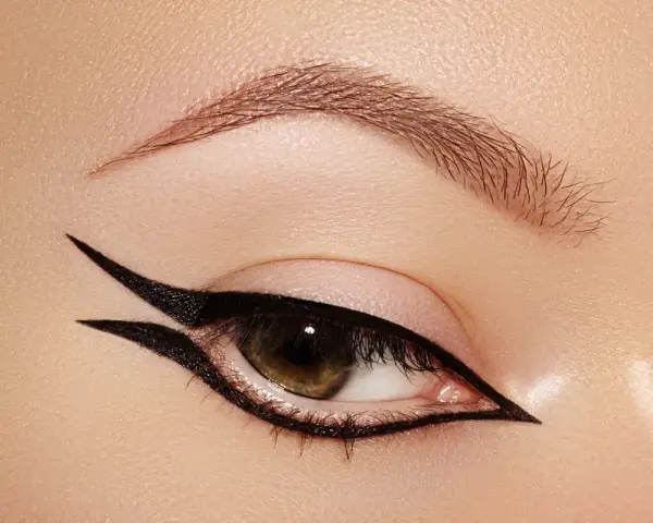 Occhio con un audace **reverse eyeliner** nero, che incornicia la palpebra inferiore e si estende verso l'alto, creando un look grafico e sofisticato.