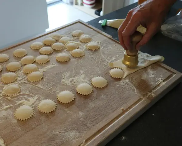 Ręcznie robione ciasto na ravioli, wycinane okrągłym wykrawaczem. Widać wiele gotowych krążków na desce.