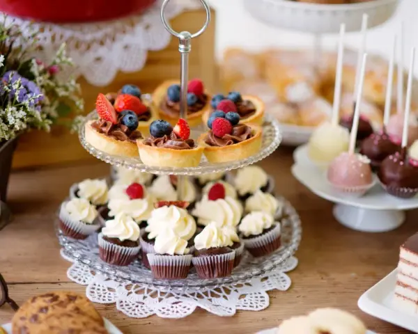 Stół z ciastkami, babeczkami, tartaletkami z owocami i cake pops.