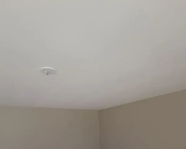 Ett vitt tak med en krok för en lampa. Väggarna är ljusbruna. Snart dags att måla taket för en fräschare känsla.