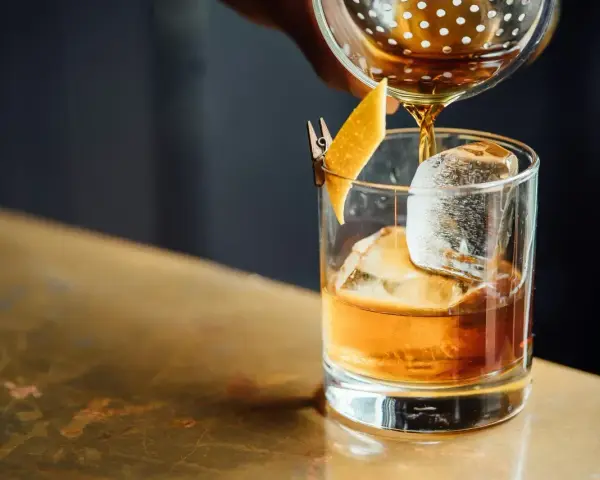 Idealny wieczór: nalewanie whisky z colą do szklanki z lodem i skórką pomarańczy.