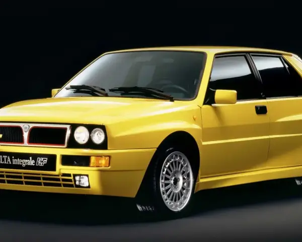 Żółta Lancia Delta Integrale HF z lat 90. na czarnym tle, z charakterystycznym grillem i felgami.