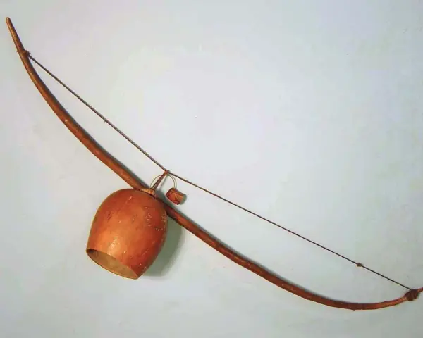 Drewniany łuk muzyczny instrument z tykwą jako pudłem rezonansowym.