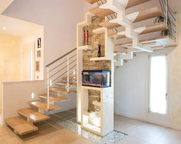 Moderna scala interna in legno e metallo, con acquario integrato e decorazioni in pietra. Un esempio di design che valorizza il costo scala interna.