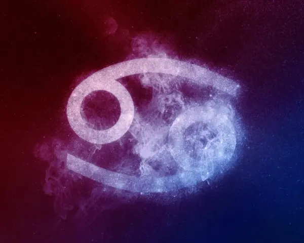 Symbol Raka, 23 czerwca znak zodiaku, otoczony kosmiczną mgławką w odcieniach czerwieni i błękitu.