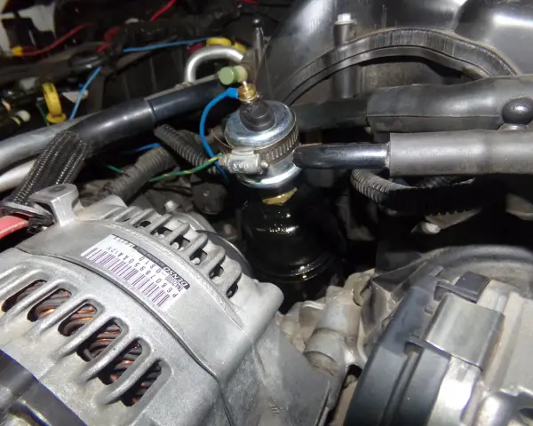 Close-up of a p0520 Dodge engine bay, showing the alternator and a fuel pressure regulator.
