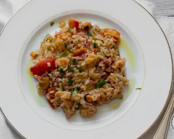 Pyszne risotto z owocami morza, z pomidorkami i natką pietruszki, polane oliwą.