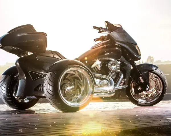 Czarny, lśniący motocykl trzykołowy z chromowanymi felgami, gotowy do podróży.
