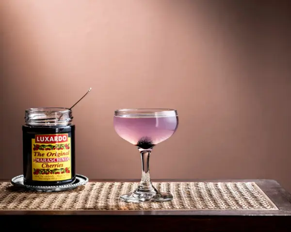 En elegant aviation drink med en burk Luxardo maraschino-körsbär, redo att förhöja smaken.