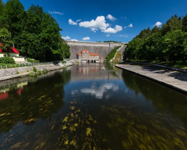 Zapora Pilchowice trasa. Malownicza droga nad zbiornikiem wodnym, z widokiem na monumentalną budowlę i otaczającą zieleń.