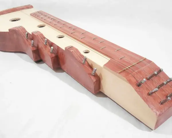 Drewniana cytra instrument z wieloma strunami i otworami rezonansowymi.
