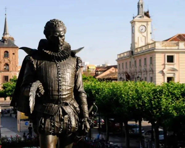 Pomnik Cervantesa w Alcalá de Henares, z ratuszem i wieżą zegarową w tle.