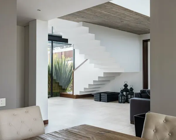 Moderna escalera blanca con un diseño flotante. El **rellano escalera decoracion descansillo escalera** se realza con linternas negras y maceteros.