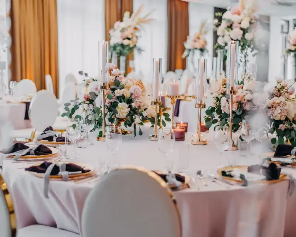 Elegancka dekoracja sali weselnej inspiracje: pastelowe kwiaty, złote świeczniki i ciemne serwetki tworzą romantyczny nastrój.