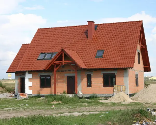 Dom w budowie z czerwonym dachem i oknami dachowymi. Wnętrze z potencjałem na wysoki, **sufit katedralny**.