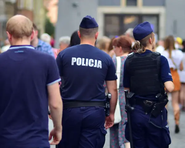 Policja w patrolu, kiedy policja szuka dłużnika. Dwóch funkcjonariuszy w mundurach idzie ulicą wśród tłumu ludzi.