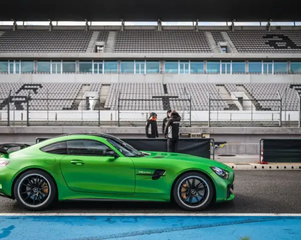 Zielony Mercedes GTR na torze wyścigowym, gotowy do jazdy. Za nim puste trybuny stadionu.