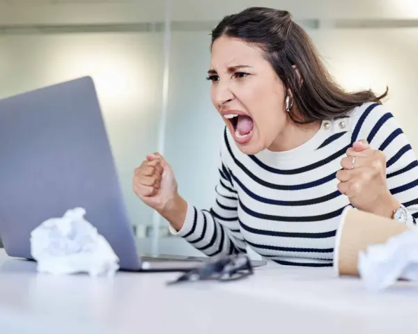 Wütende Frau schreit vor Laptop, frustriert über Probleme im **bad neighbourhood**.