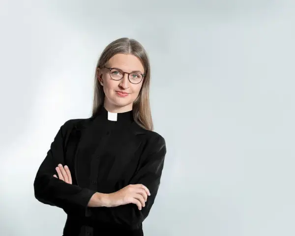 Eine Frau mit Brille und Kragen, die zeigt, dass Pfarrer Beamte sind.