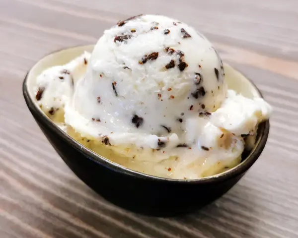 Ein Löffel cremiges Stracciatella-Eis mit zarten Schokoladenstückchen in einer Schale.