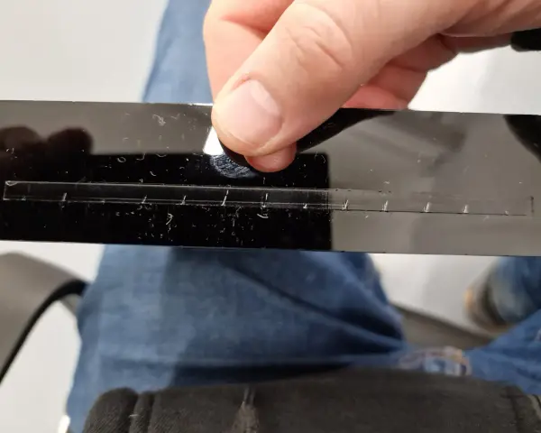 A hand holds a black acrylic strip with a precisely cut slot, demonstrating how to laser cut acrylic at home.