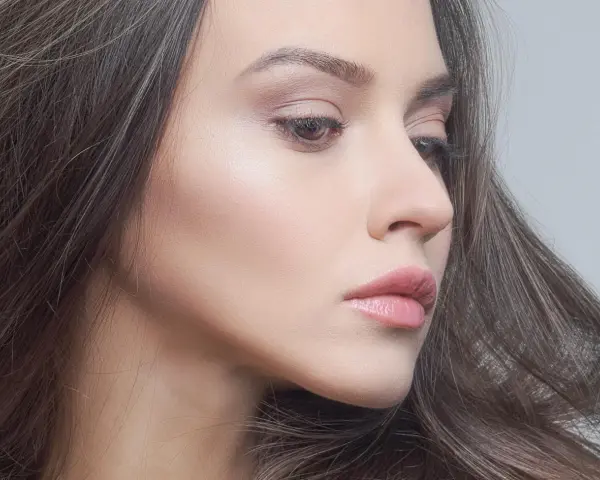 Delikatny makijaż glow podkreślający naturalne piękno. Skóra promienieje subtelnym blaskiem, a usta są muśnięte różowym błyszczykiem.