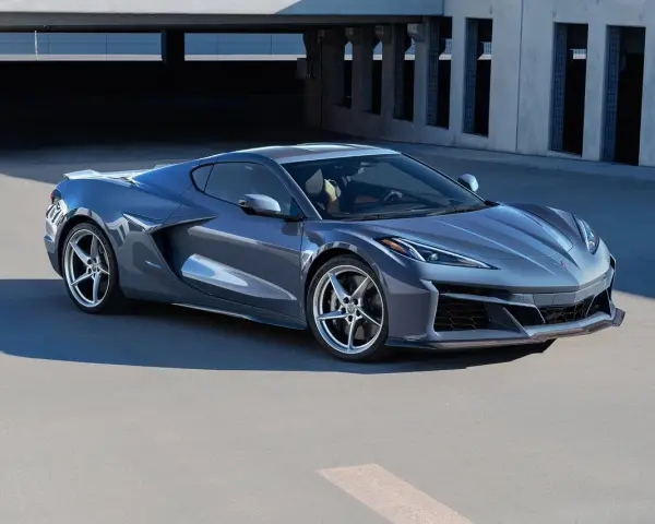 Szary Chevrolet Corvette Stingray z nowoczesnym designem, zaparkowany na tle betonowej architektury.