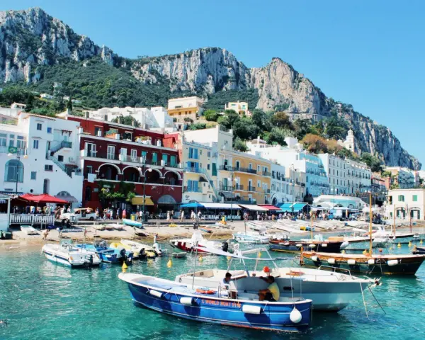 Vue pittoresque de Capri, un joyau pour votre naples voyage. Bateaux colorés dans une eau turquoise, face aux maisons et aux falaises majestueuses.