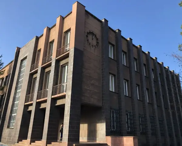 Imponujący budynek w stylu modernizm architektura, z ciemnymi płytkami i jasnymi akcentami, ozdobiony zegarem.