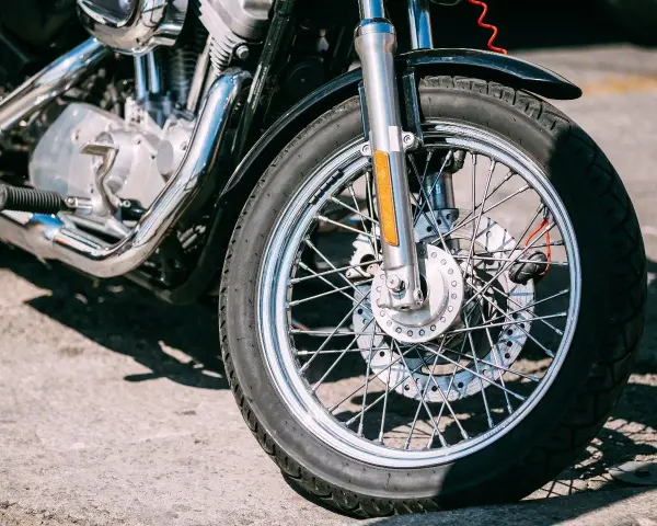 Zbliżenie na koło motocykla z widocznym silnikiem i chromowanymi elementami.