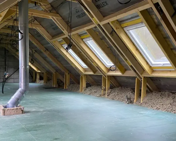 Aménagement des combles d'une maison Phénix : charpente, fenêtres de toit, isolation et gaine de ventilation en cours.