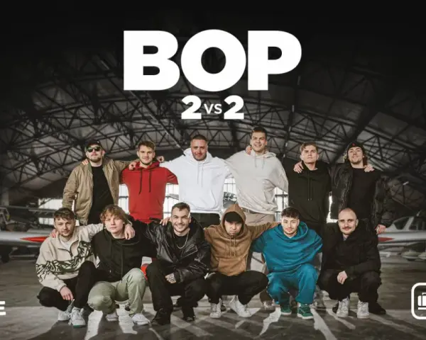Dziesięciu młodych mężczyzn pozuje w hangarze lotniczym, gotowych na bitwę o południe. W tle samoloty, a na górze logo BOP 2 vs 2.