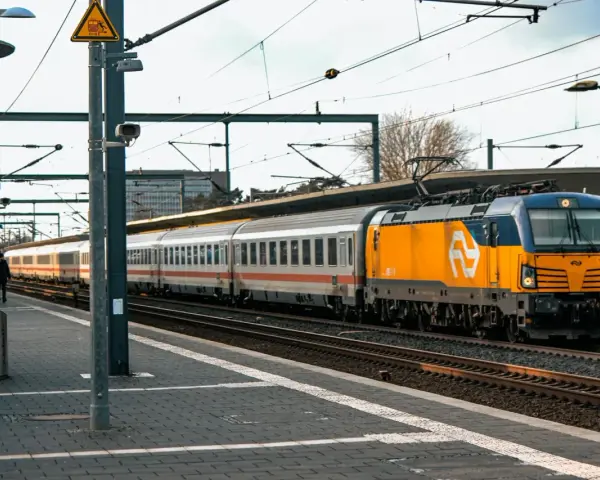 Pociąg Berlin Warszawa Express z żółto-niebieską lokomotywą na peronie.